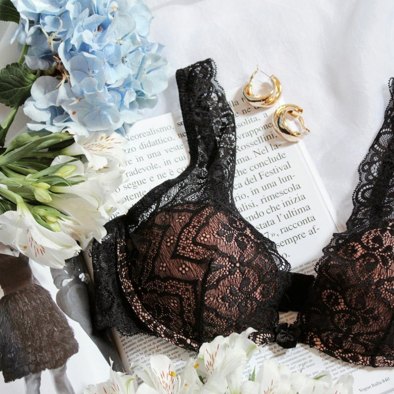 Elegant black lace bra with flowers and gold earrings, creating a romantic and sophisticated ambiance.