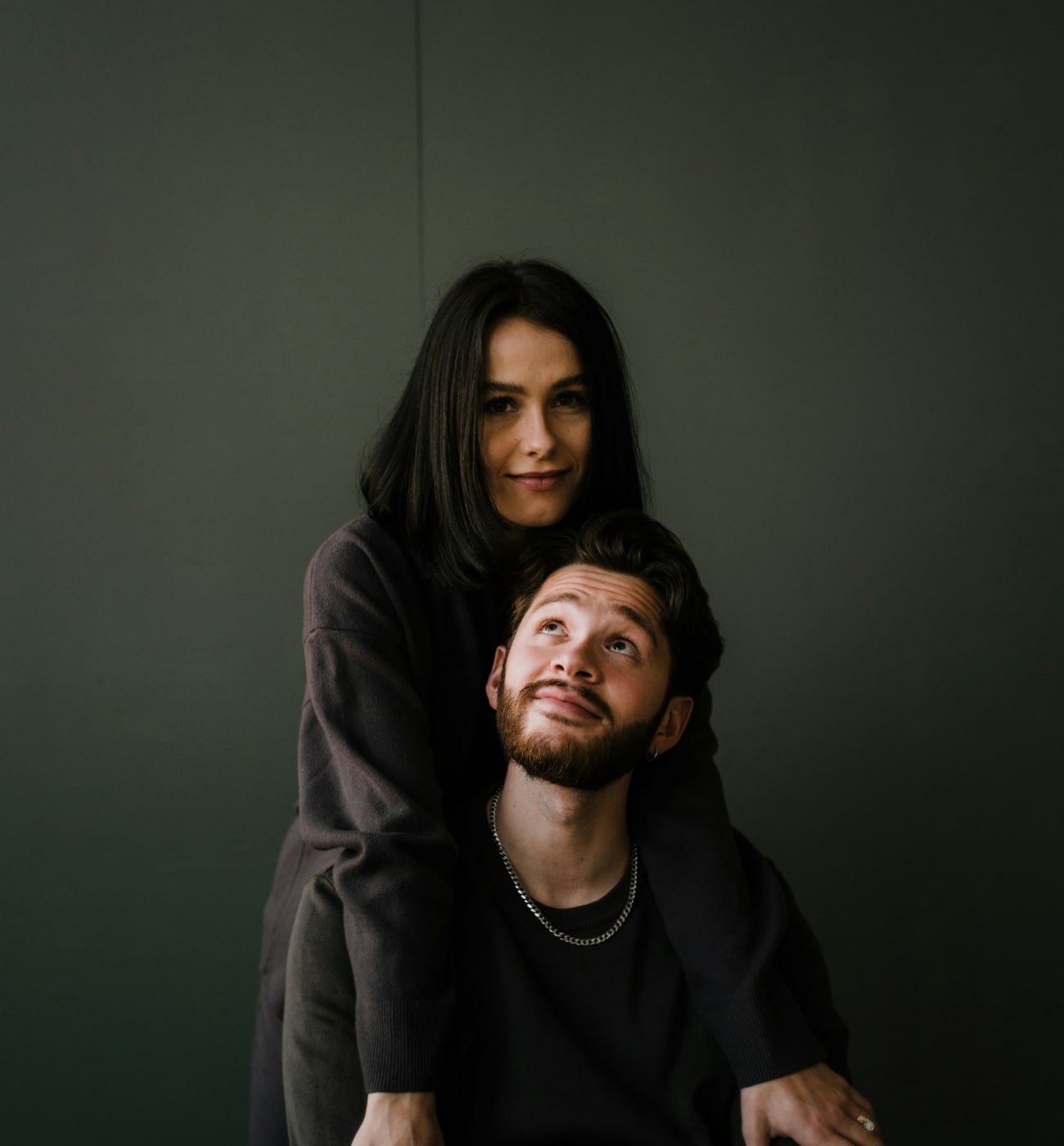 Intymny portret pary na tle głębokiej zieleni, ukazujący ciepło i więź.