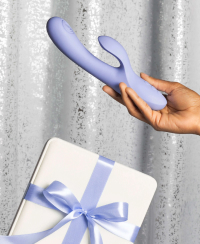 Lavender silicone vibrator with gift box, set against a glamorous sequined backdrop, embodies intimacy.