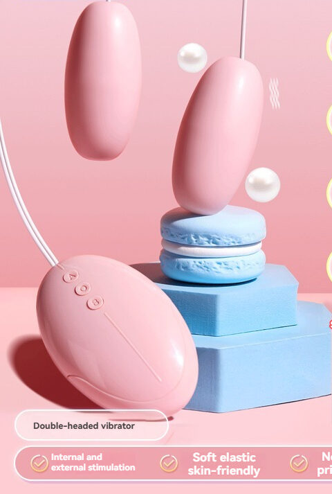 Durex dobbelthovedet vibrator i pink med macarons, der viser luksuriøse og legende intimitetsprodukter.