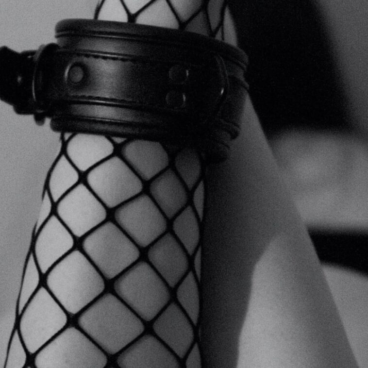 Elegant black fishnet stockings and a leather cuff create a striking edgy fashion statement.