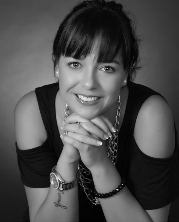 Confident young woman smiling, styled in black with elegant accessories against a gradient background.