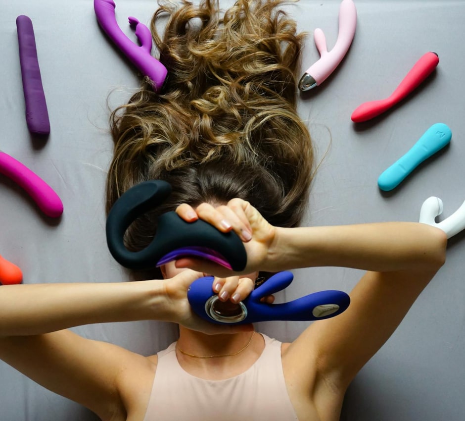 Anonymous figure surrounded by colorful sex toys, celebrating personal pleasure and self-expression.