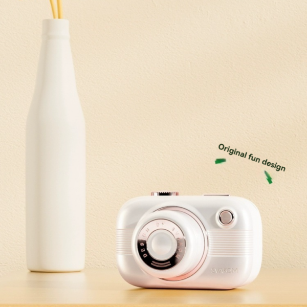 Stylish white camera and cheerful flowers on wood, perfect for photography inspiration and design lovers.