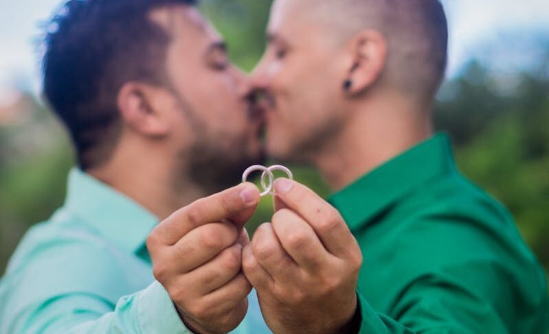 A loving couple holding their engagement rings outdoors, showcasing affection and commitment.