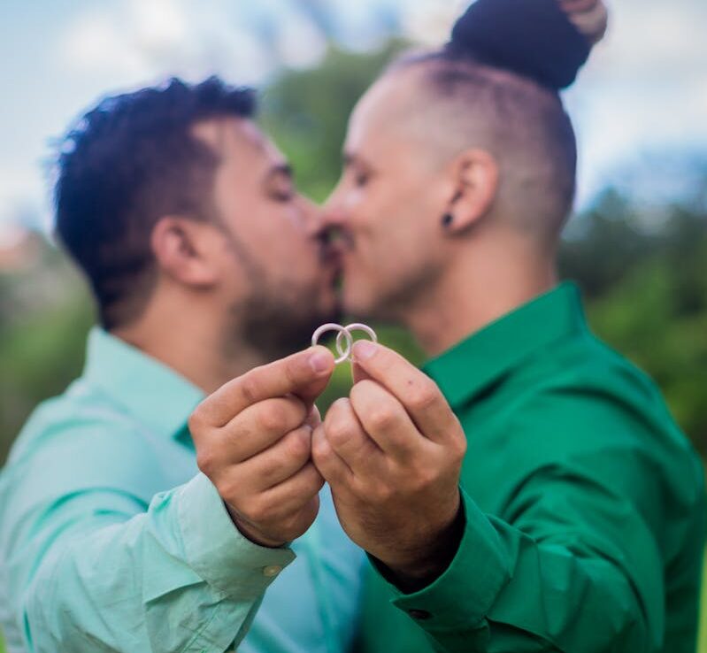 A loving couple holding their engagement rings outdoors, showcasing affection and commitment.