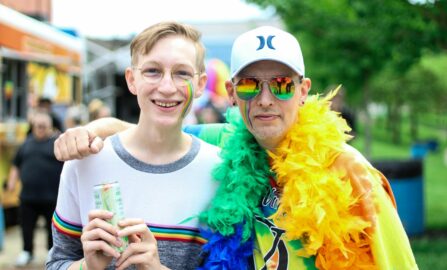 Celebrazione dell'orgoglio gioioso della comunità e dell'inclusione Due persone che si sorridono e si abbracciano in una vibrante festa dell'orgoglio all'aperto con i colori dell'arcobaleno.