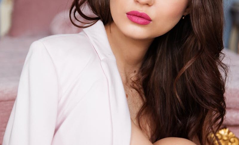 Close-up portrait of a stylish woman with glamorous makeup and pink lipstick, indoors.