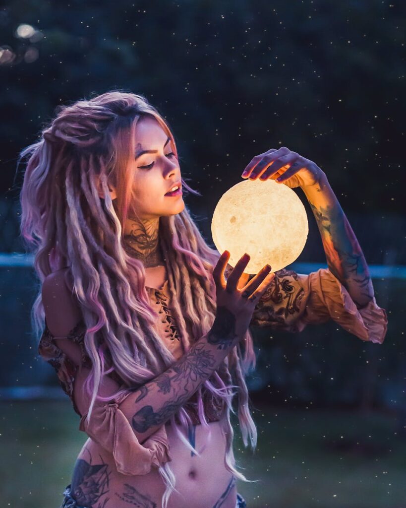 Portrait fantaisiste en extérieur d'une femme tatouée tenant un orbe lumineux, évoquant le mystique et le fantastique.