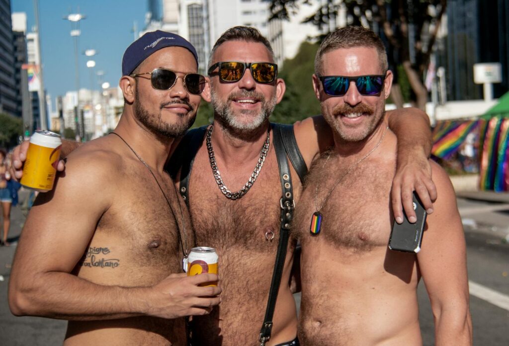 Três homens a celebrar o orgulho LGBT ao ar livre em São Paulo, Brasil.