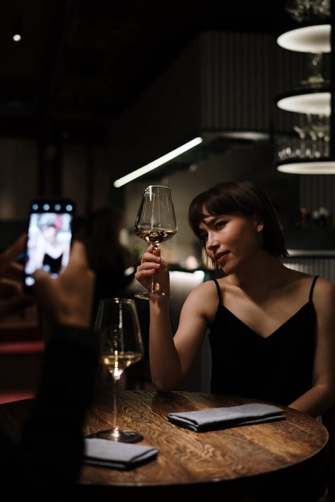 Woman enjoying a glass of white wine during a romantic dinner at an upscale restaurant.