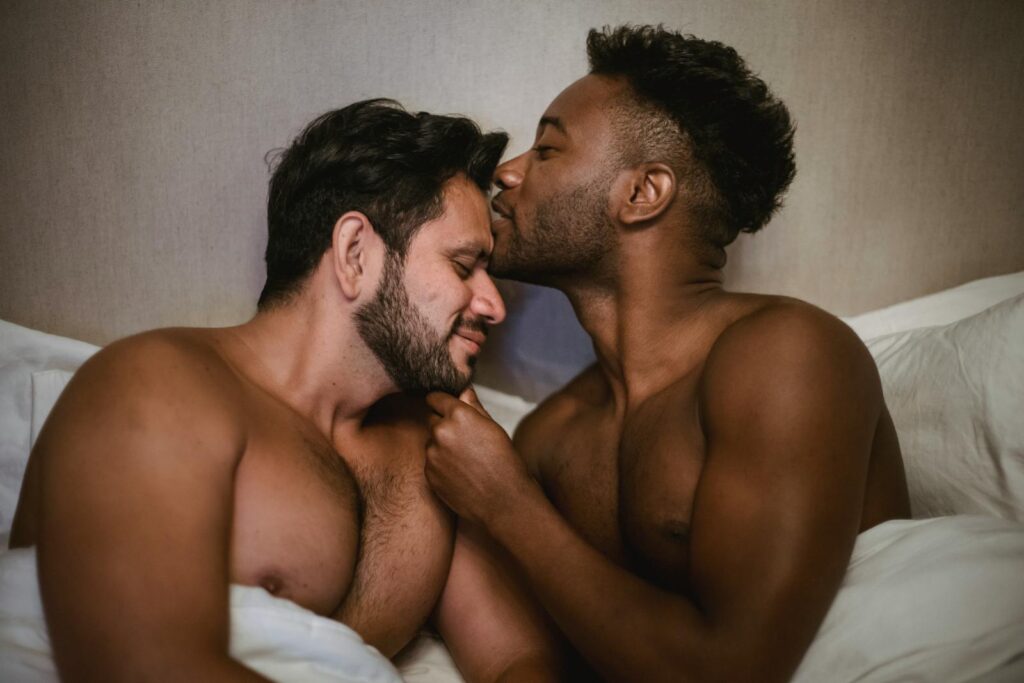 A tender moment shared by an affectionate interracial couple in bed, expressing love and intimacy.