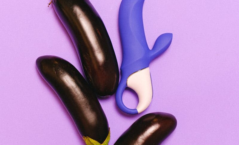 Vibrant image of eggplants and a blue vibrator on purple background.