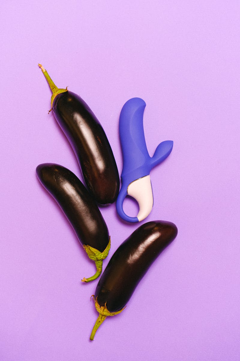 Immagine vibrante di melanzane e di un vibratore blu su sfondo viola.
