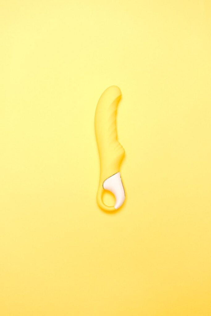 A yellow silicone vibrator displayed on a matching colored background, showcasing modern intimacy products.