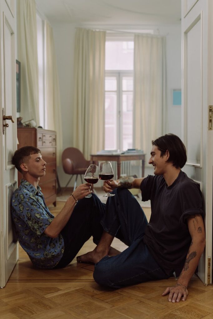 A loving couple sitting indoors, sharing wine and smiles in a cozy setting.