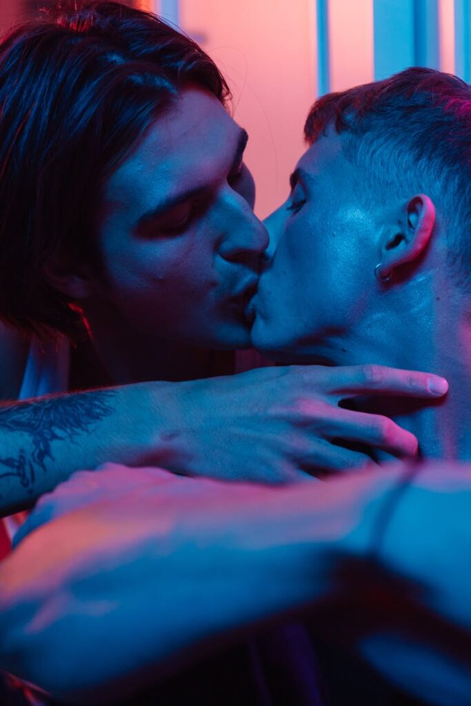 A tender moment captured as two men share a kiss under vibrant neon lighting, symbolizing love and inclusivity.