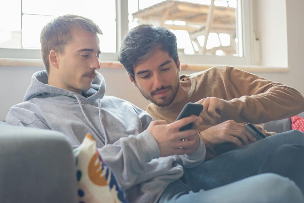 A couple enjoying a relaxing moment while using a smartphone at home. Cozy and intimate.