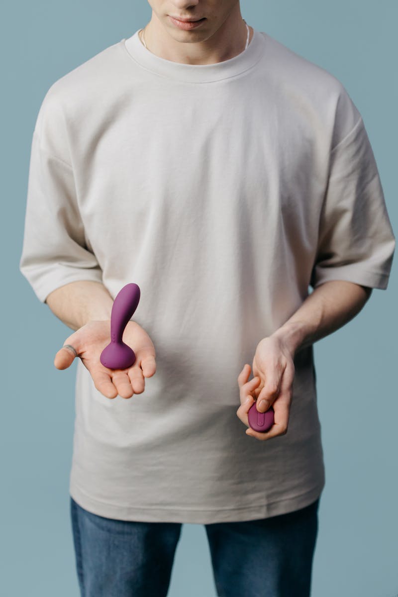 Voksen med to forskellige lilla vibratorer, der fremmer selvkærlighed og seksuel velvære.