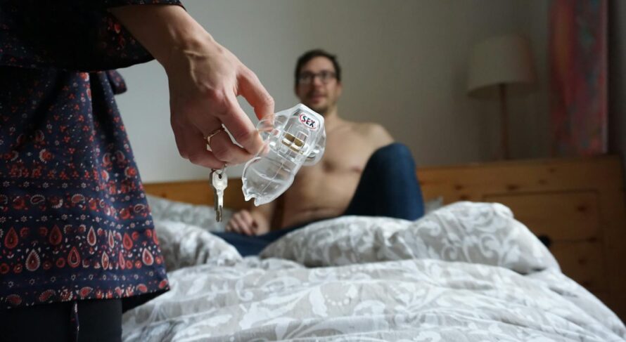 Intimate moment in a bedroom featuring a couple and a clear cage device.