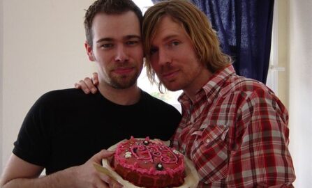 Due amiche festeggiano gioiosamente con una torta vivace, condividendo risate e calore in un accogliente ambiente interno.