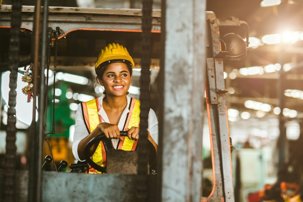 Americano nero donne lavoro lavoratore a carrello elevatore driver felice di lavorare in fabbrica industria logistica nave