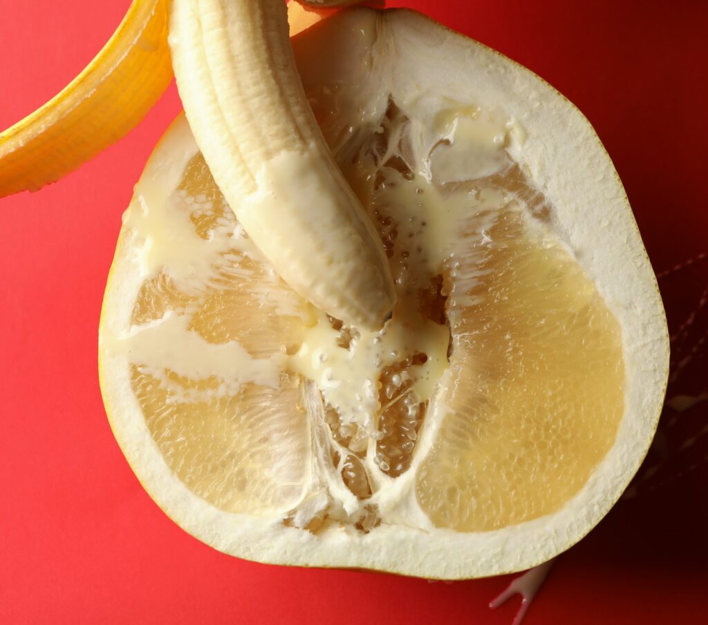 Banana with condensed milk on pomelo fruit on red background