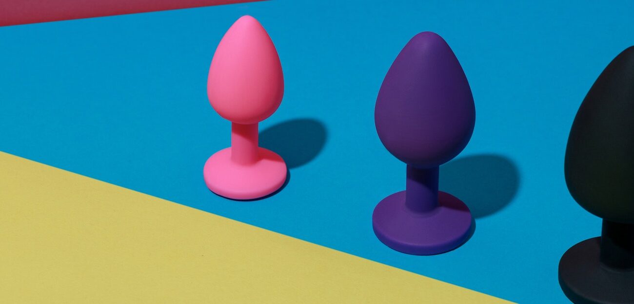 Vibrant Anal Toys Against a Bold Geometric Background Different colored buttplug sex toys with contrast shadows. Anal toys for adult. Sex shop concept
