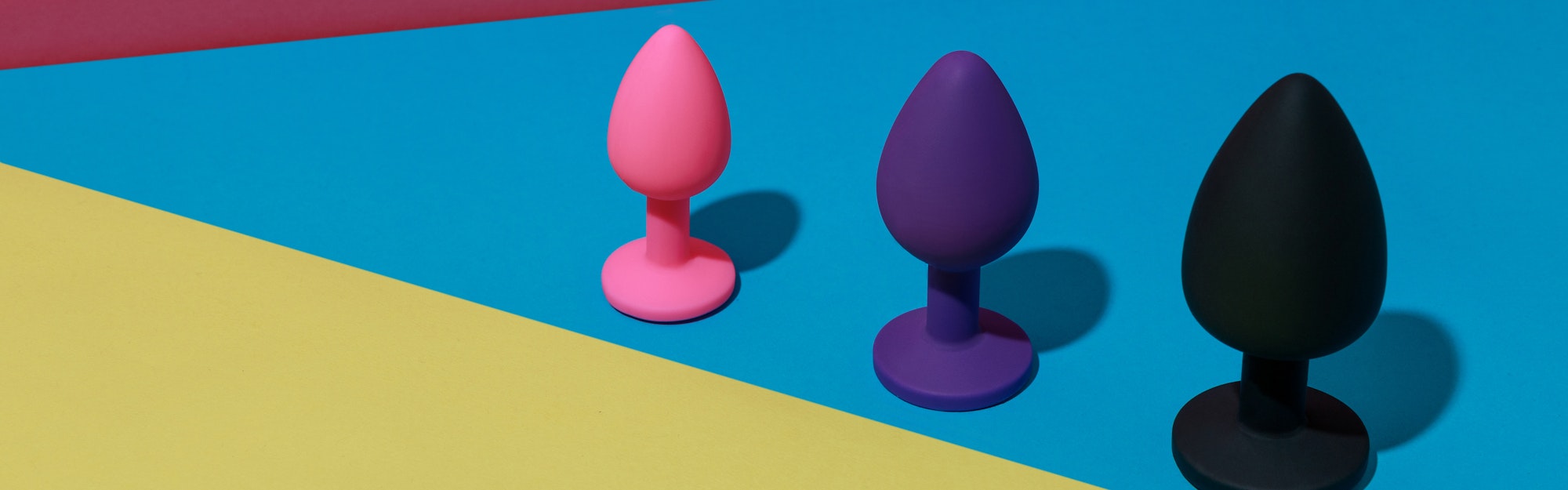 Forskelligt farvet buttplug-sexlegetøj med kontrastskygger. Anallegetøj til voksne. Koncept for sexbutik