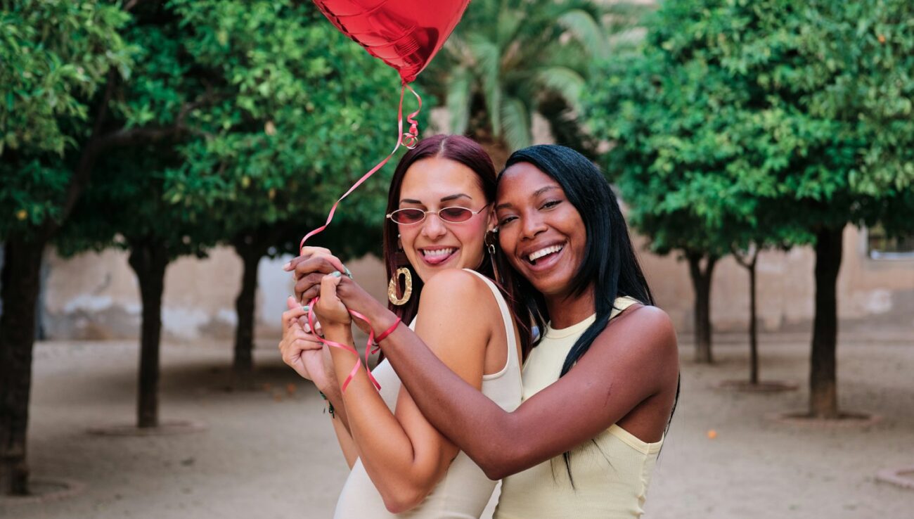 Couple de lesbiennes heureux avec un ballon rouge en forme de coeur.