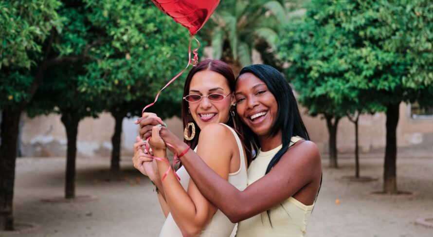 Happy lesbian couple with a red heart-shaped balloon.