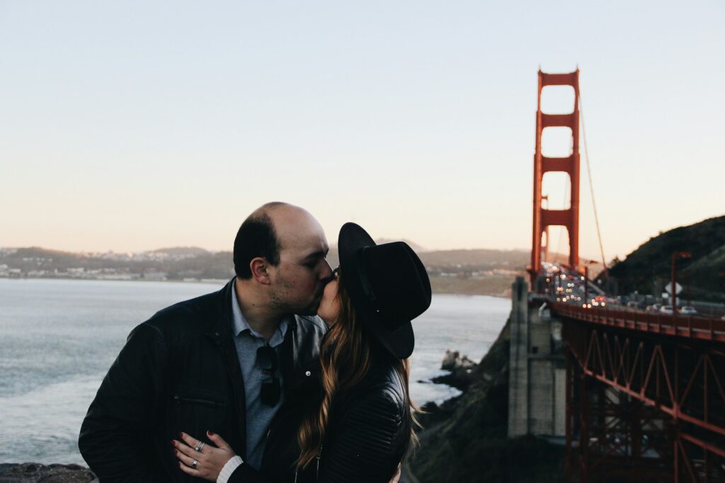 hombre y mujer besándose junto al puente Golden Gate durante el día