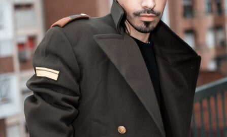 un uomo con capelli e barba neri che indossa un cappotto