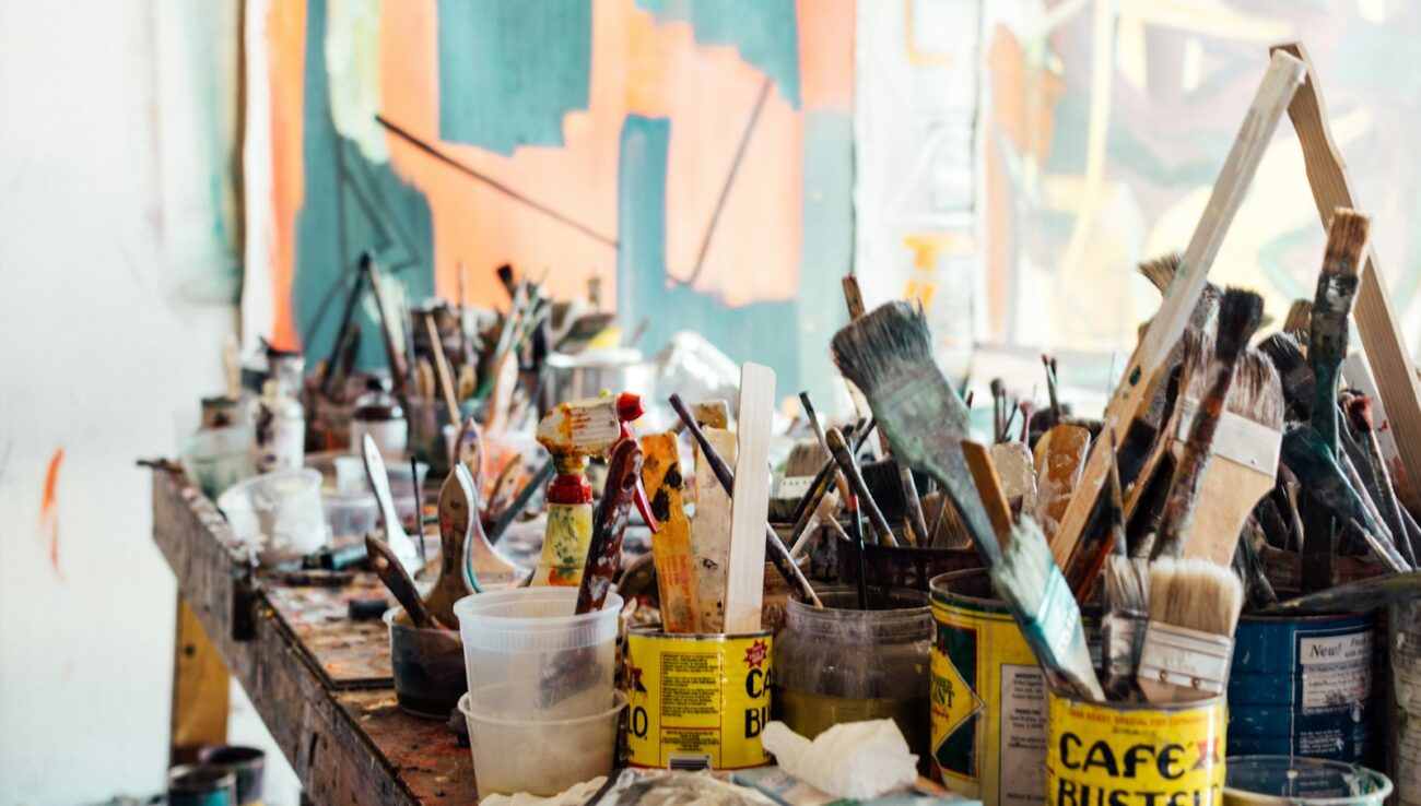 assorted-color paint brush on brown wooden table top