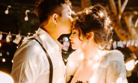 Momento romantico sotto le luci scintillanti delle fate uomo che bacia la fronte della donna