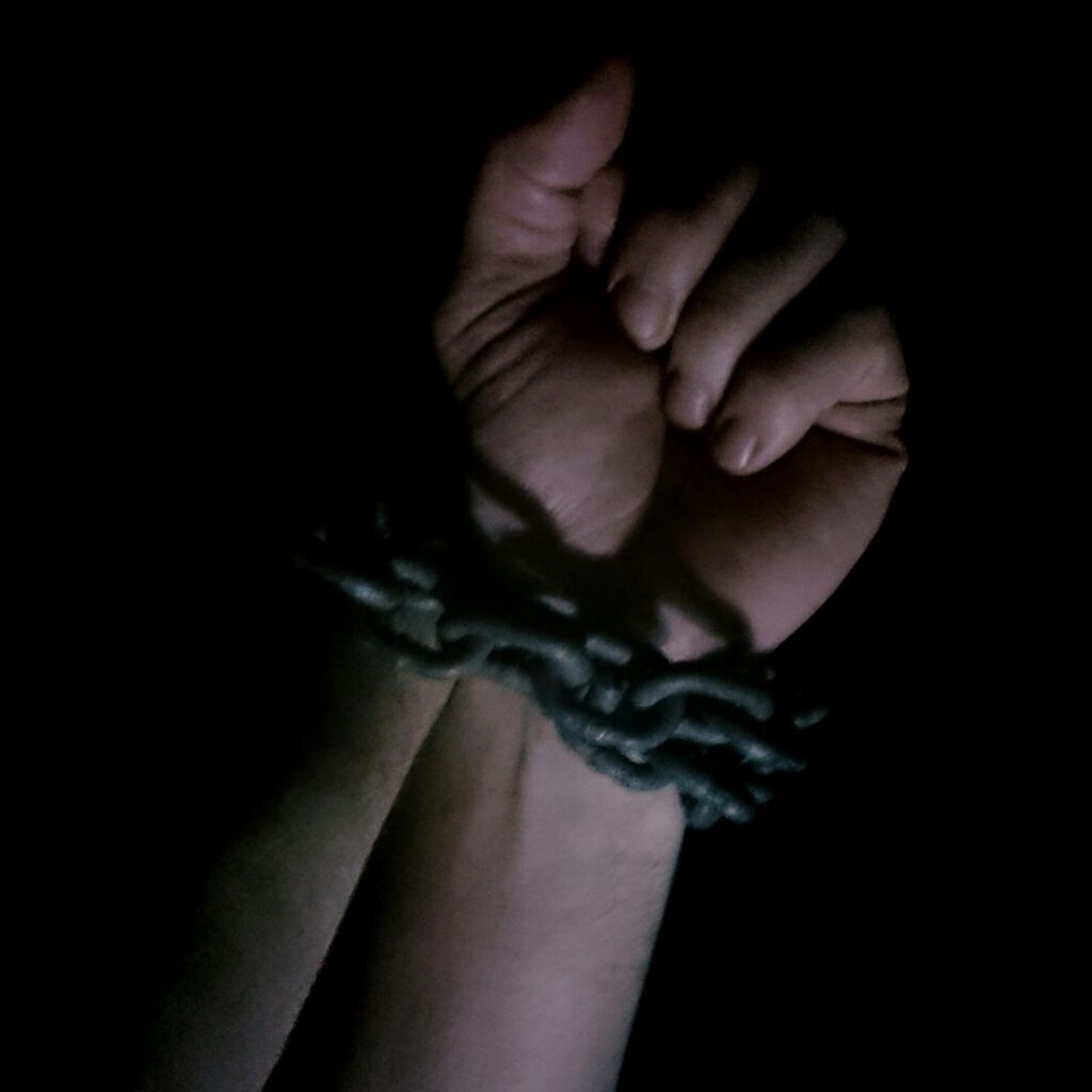 Male hands handcuffed with chains, shadow and mystique, drama, bdsm, abuse, violence, mistreated