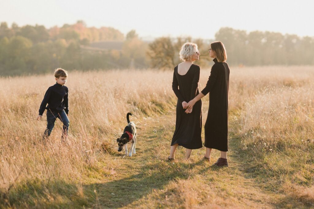 Famille de lesbiennes caucasiennes du même sexe avec un enfant et un chien se promenant à l'extérieur