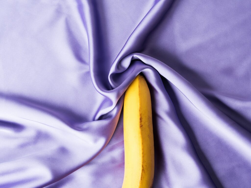 Sex and orgasm concept with banana on crumpled silk sheet