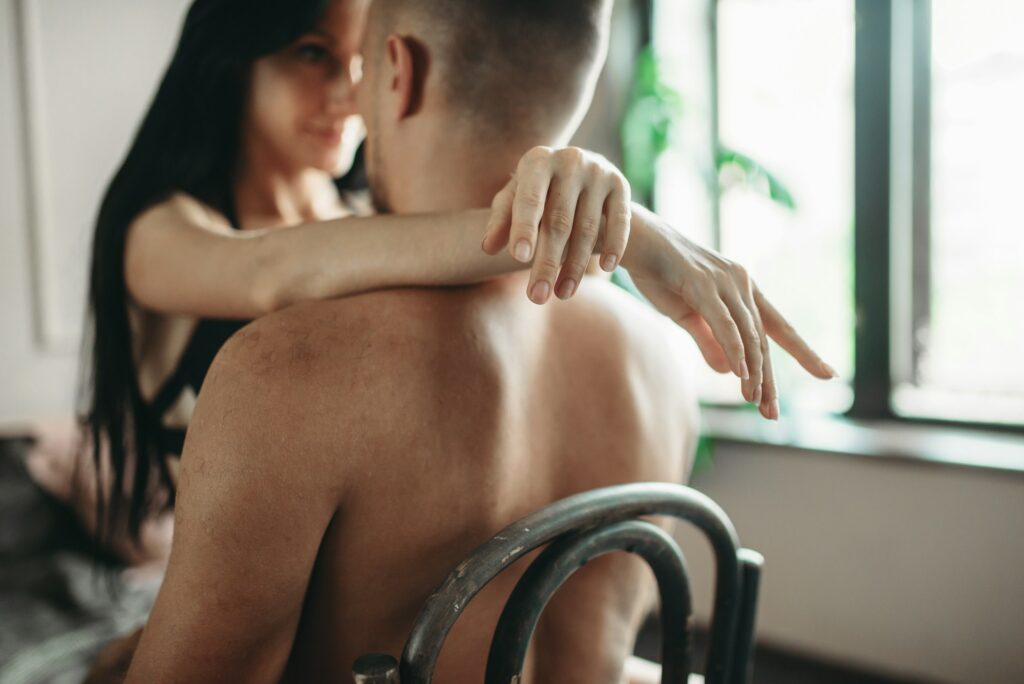 Sexy couple in underwear hugs on a chair, erotica