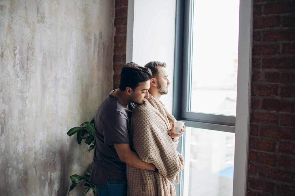 two handsome homosexual guys while standing near window