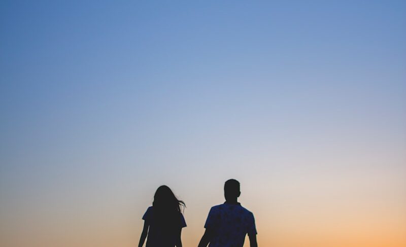 man and woman holding hands in silhouette photography