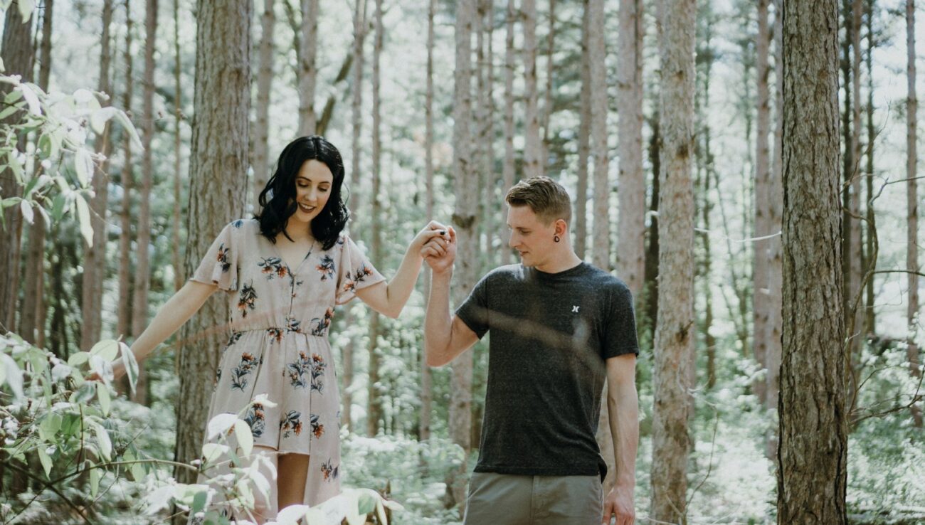 man holding hands with woman near trees