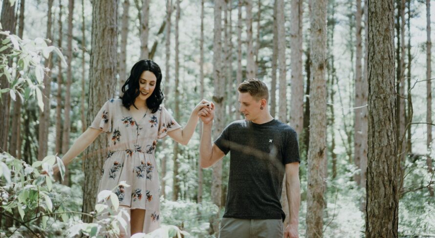 man holding hands with woman near trees