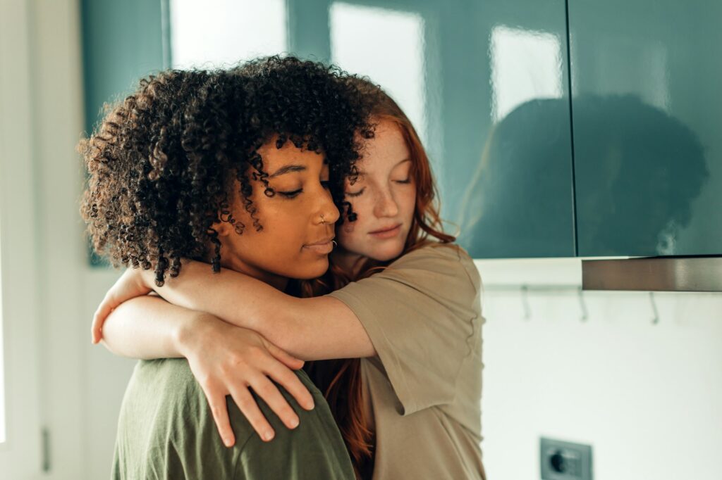 una joven pareja de lesbianas enamoradas se abraza tiernamente en casa