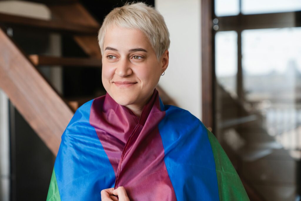 Young woman hipster with short haircut lesbian female covering with LGBT flag.