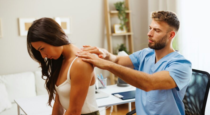 Young woman with neck pain is being examined by a physiatrist