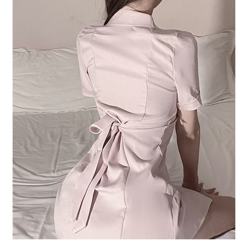 Elegante vestido rosa sobre la cama, mostrando moda íntima para un ambiente seductor en el dormitorio.