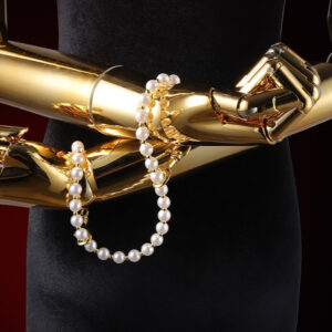 Gold mannequin arms displaying pearl jewelry for elegant adult accessories showcase.