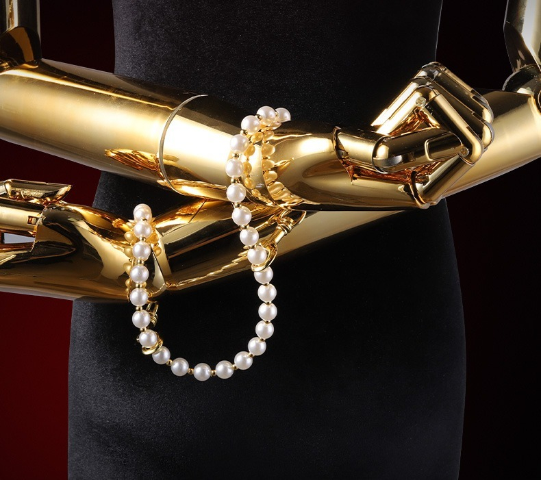 Gold mannequin arms displaying pearl jewelry for elegant adult accessories showcase.