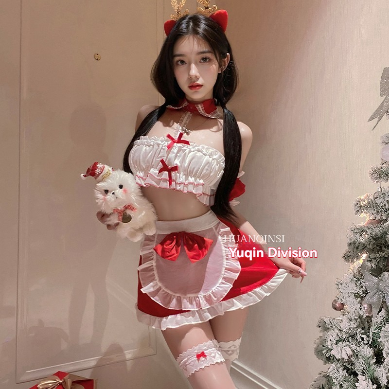 Ragazza in costume festivo con simpatiche orecchie da gatto e accessori festivi accanto a un albero di Natale decorato.